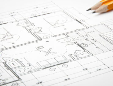 Construction planning drawings on the table and two yellow pencils